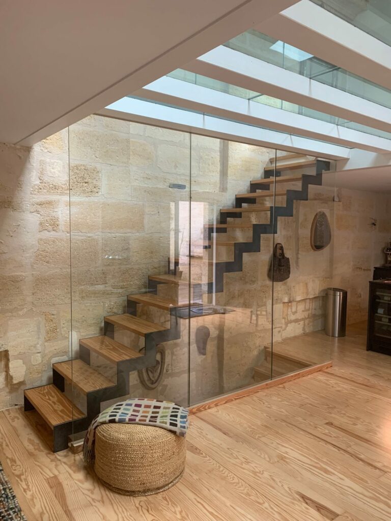 Cloison en verre toute hauteur posée devant un escalier dans une maison en pierre à Bordeaux