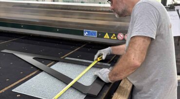 Découpe verre sur mesure : un miroitier MSO contrôle les cotes d’un gabarit dans l’atelier de Lormont