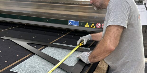 Découpe verre sur mesure : un miroitier MSO contrôle les cotes d’un gabarit dans l’atelier de Lormont