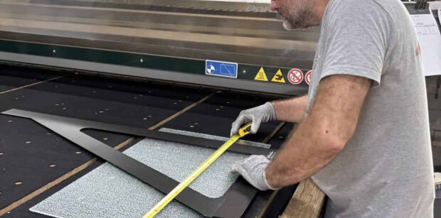 Découpe verre sur mesure : un miroitier MSO contrôle les cotes d’un gabarit dans l’atelier de Lormont