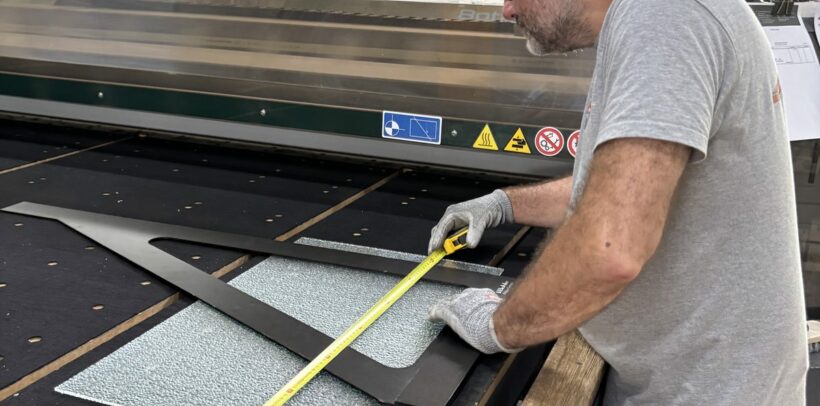 Découpe verre sur mesure : un miroitier MSO contrôle les cotes d’un gabarit dans l’atelier de Lormont